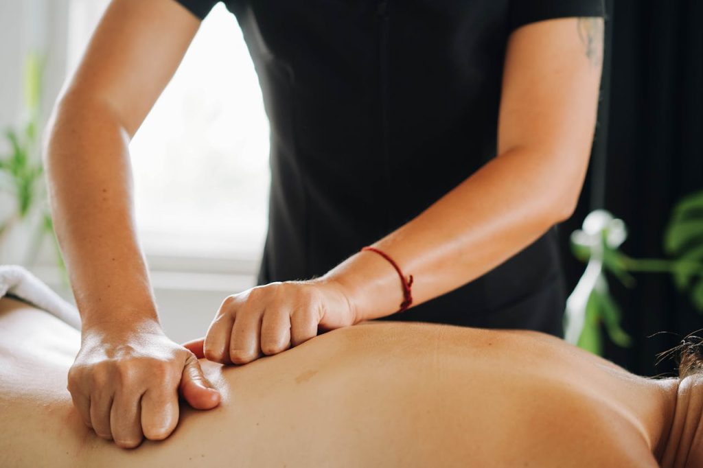 therapist-massaging-client-s-back-9336026 Close-up of a therapist performing a calming knuckle massage at a spa.
